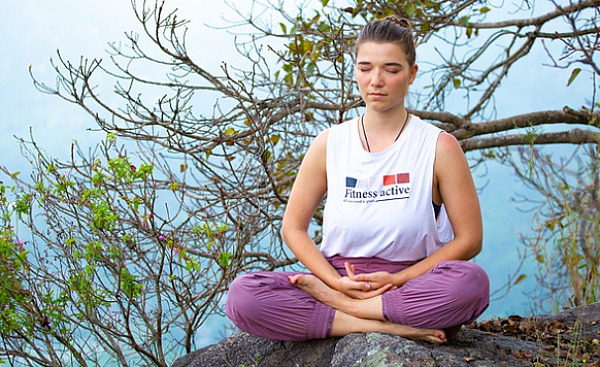 young woman sitting outside in a meditation position